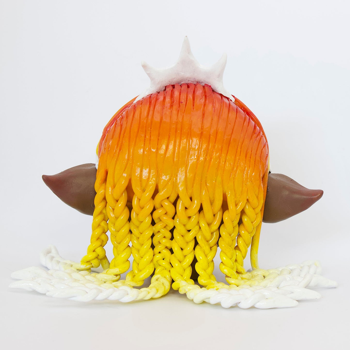 Polymer clay sculpture of a sun elf head, featuring a sun shaped crown, braided hair in a gradient from red, to orange, to yellow, to white.