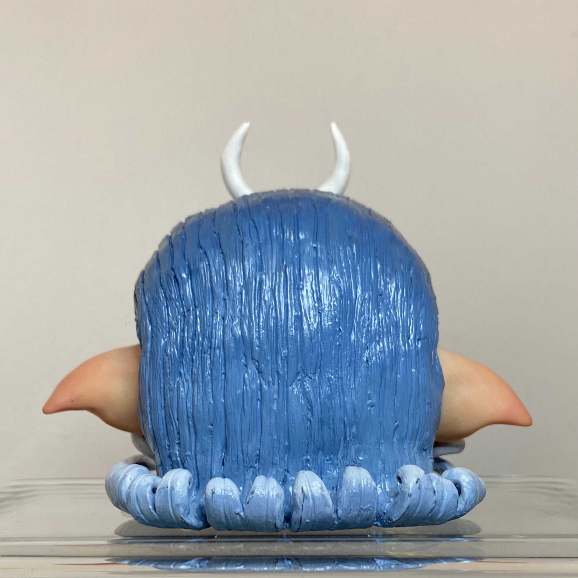 Polymer clay sculpture of a moon elf head, featuring a moon shaped crown, hair in a gradient from dark blue to light blue. 