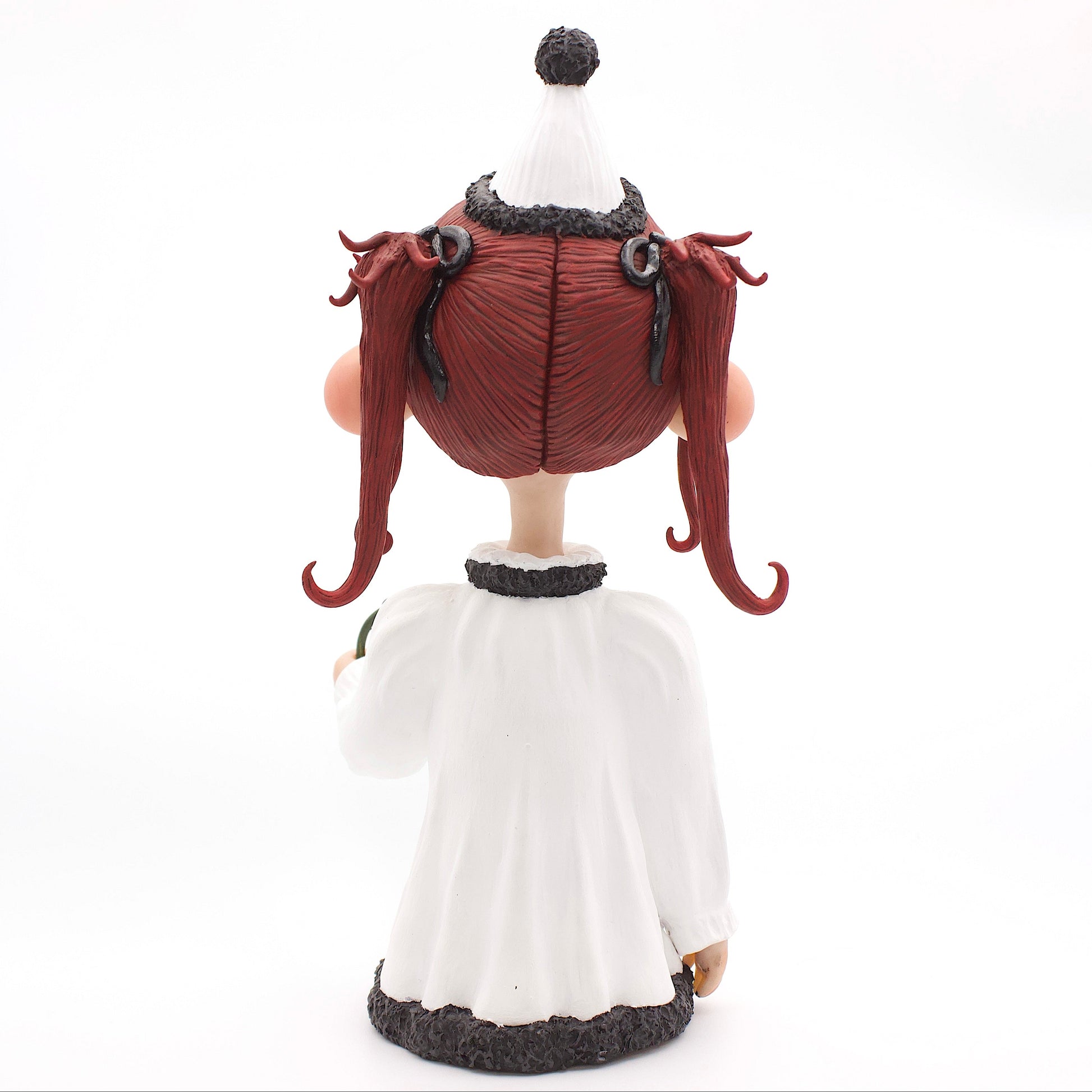 A polymer clay sculpture of a sad pierrot girl clown, holding a drooping rose, wearing the iconic pierrot clown garb in black white and red.