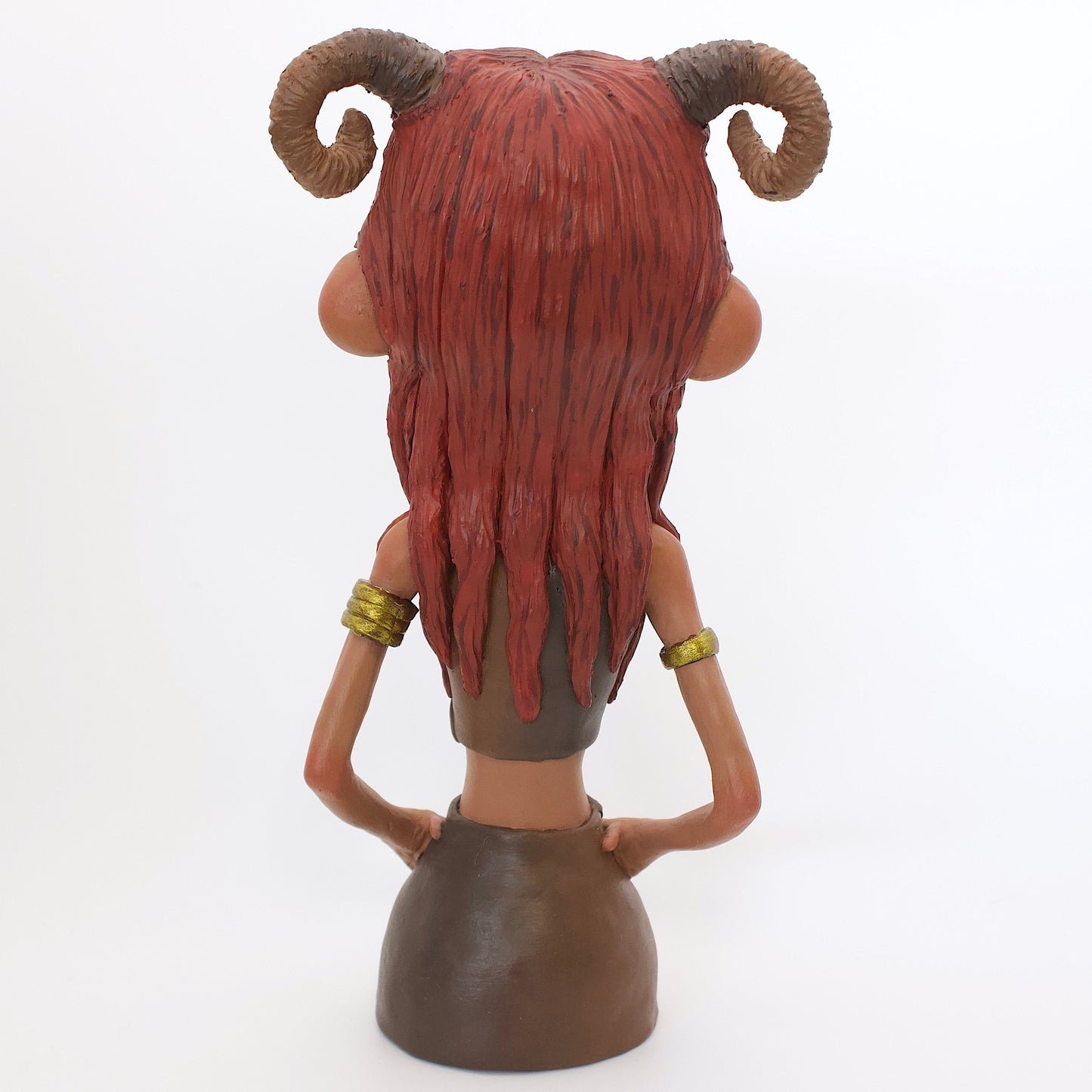 A polymer clay sculpture of the Aries zodiac personified as a woman, featuring red toned browns, long red brown hair and the iconic ram horns.