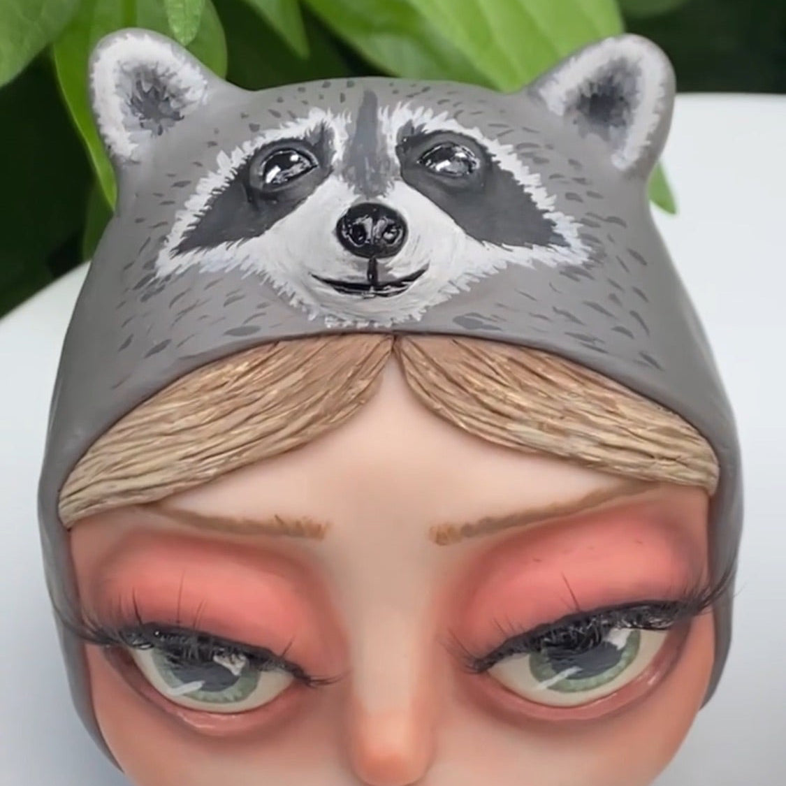 A commissioned polymer clay sculpture of a girl wearing a raccoon beanie and her dog.