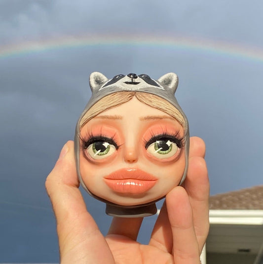 A commissioned polymer clay sculpture of a girl wearing a raccoon beanie and her dog.