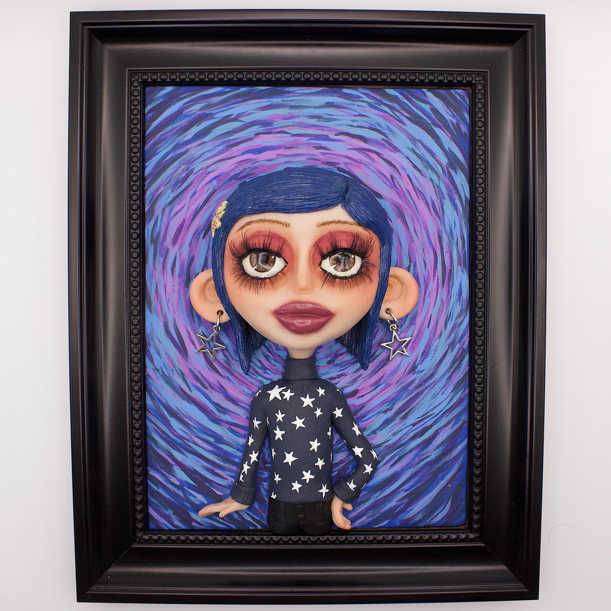 A polymer clay sculpture positioned in a black wood photo frame. Featuring Coraline in her iconic blue star sweater, set against an impressionistic view of the tunnel to the other world. 