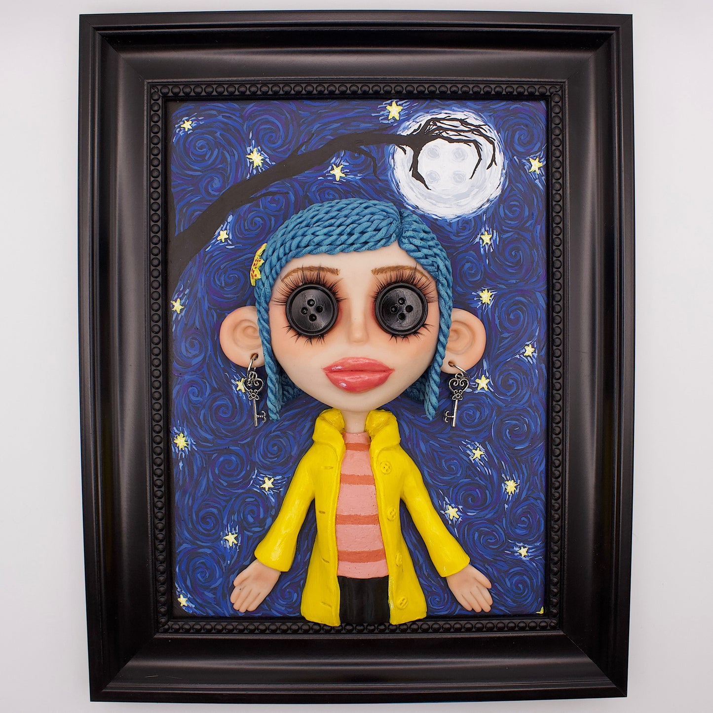 A polymer clay sculpture positioned in a black wood photo frame. Featuring the Coraline doll with her iconic button eyes, in her yellow raincoat, set against an impressionistic view of the starry sky with the button moon and a gnarled tree branch in the shape of the other mothers hand. 