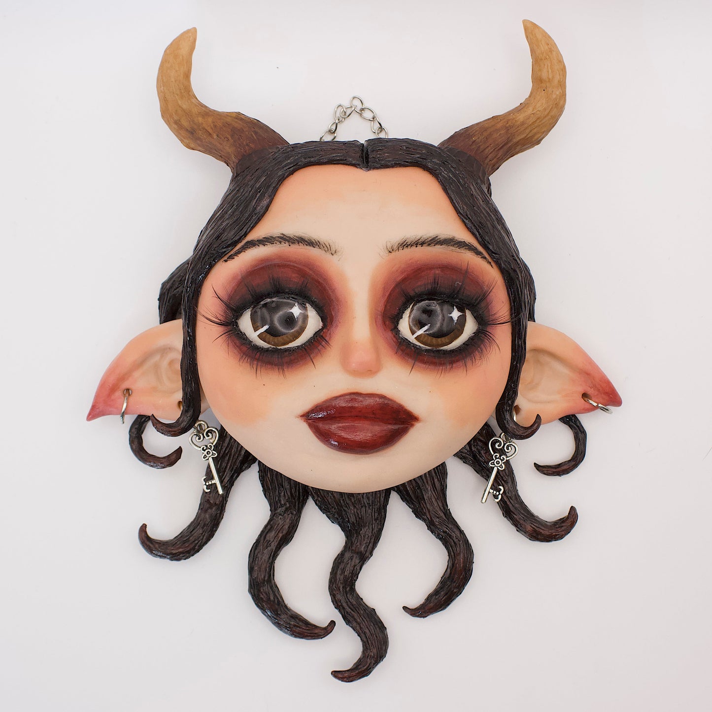 Wall hanging polymer clay sculpture portraying Lilith, the queen of hell. Featuring horns, elf ears and black serpentine hair. 