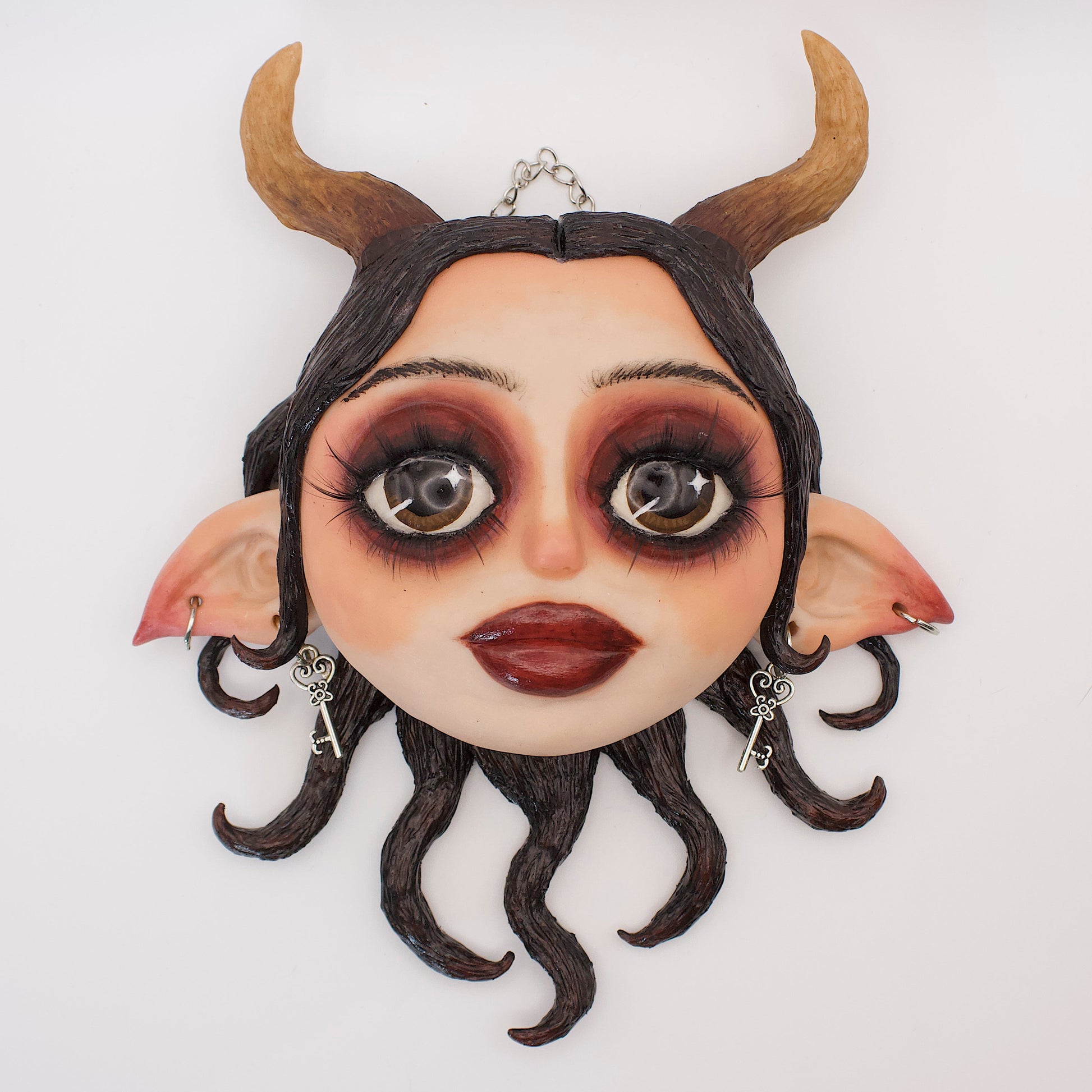 Wall hanging polymer clay sculpture portraying Lilith, the queen of hell. Featuring horns, elf ears and black serpentine hair. 