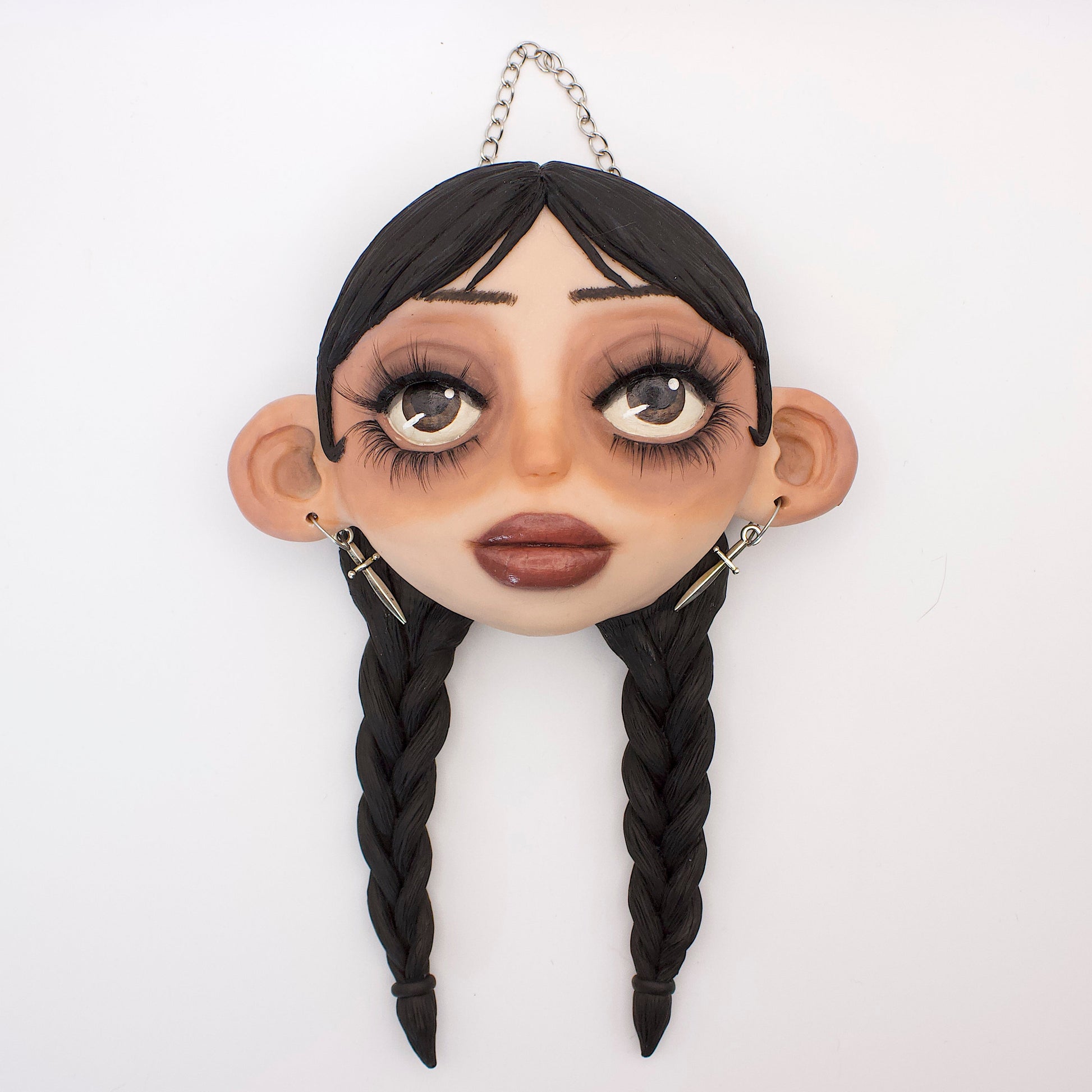 Wall hanging polymer clay sculpture of Wednesday Addams, featuring her iconic braided hair and dead pan expression
