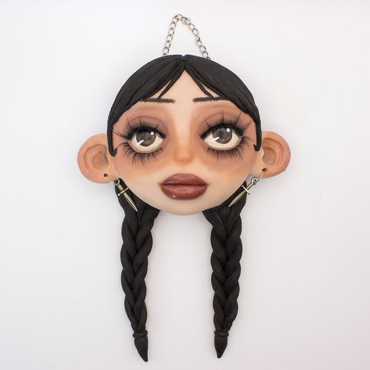Wall hanging polymer clay sculpture of Wednesday Addams, featuring her iconic braided hair and dead pan expression